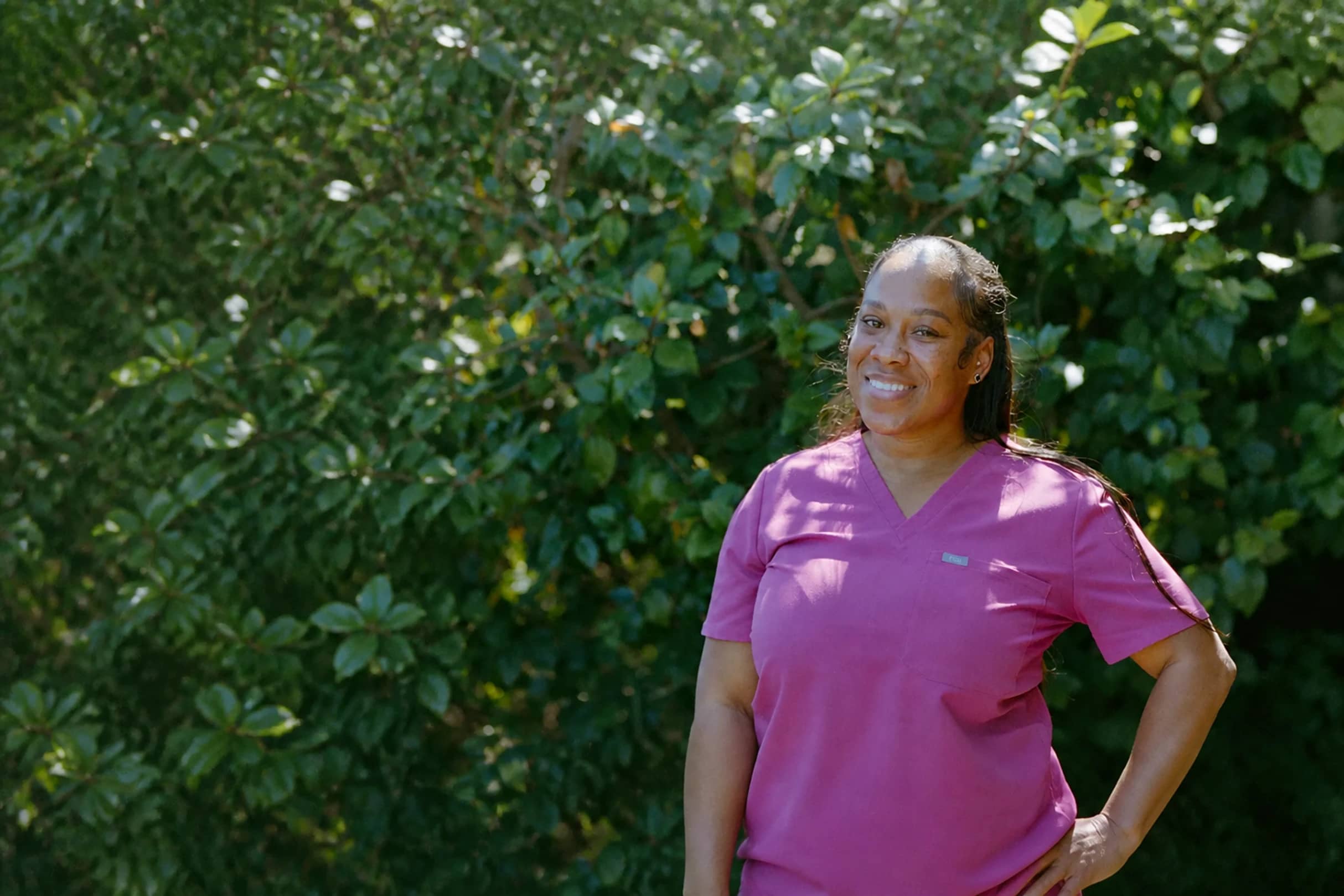 Healthcare professional in scrubs smiling outdoors
