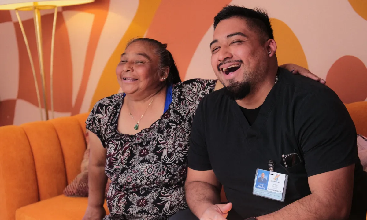 A CNA sits with a smiling patient